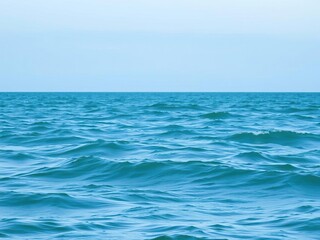 Fototapeta premium A vast turquoise green body of water with gentle rolling waves and ripples under a light blue evening sky, calm, water, peaceful
