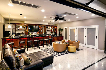 A spacious garage converted into a luxurious man cave with a bar, lounge, and entertainment options.