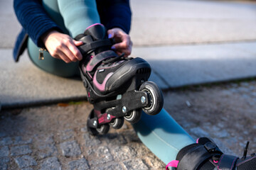 Woman fastening inline skates before skating in urban setting