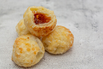 Brazilian cheese bread with sweet goiabada filling piled on a textured surface.