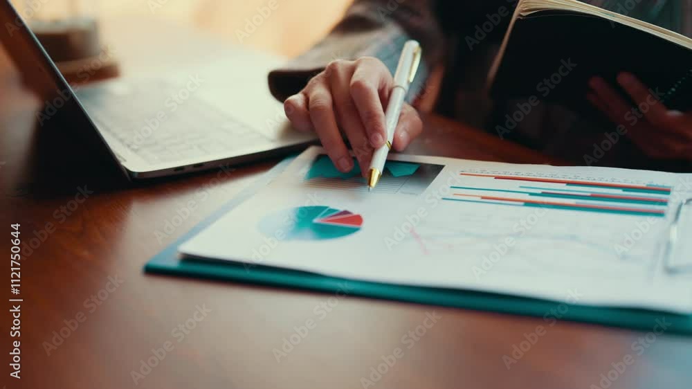 Leinwandbilder Businesswoman reviewing financial reports and graphs, highlighting key figures with a pen, and taking notes in a notebook while analyzing data in an office setting