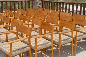 Group of empty wooden vintage chairs with rattan seats arranged in rows before an event. Many...