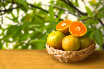 Oranges  on a wooden table The background is a garden with green leaves.