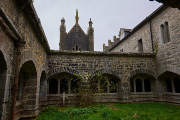 Fototapeta premium Courtyard of Augustinian Friary in Adare, Ireland, surrounded by arched stone cloisters and historic architecture