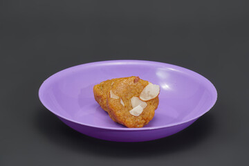 Two pieces of Mohanthal, on a a small purple plate, a traditional gujarati sweet