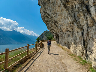 Hiker woman on hiking trail Sentiero del Ponale with scenic view of Garda Lake, Trentino, Northern...