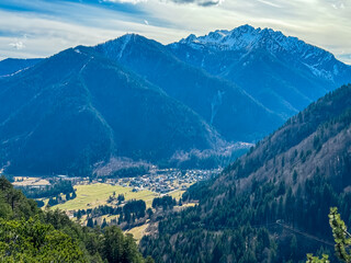 Aerial view of remote valley Val Saisera and alpine village Malborghetto Valbruna surrounded by snow capped mountains peaks of Julian Alps, Friuli Venezia Giulia, Italy. Wanderlust in Italian Alps