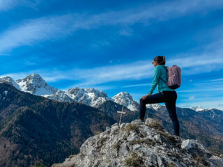 Hiker woman with panoramic view of snow capped mountain peaks of Julian Alps seen from top of Monte Nebria, Friuli Venezia Giulia, Italy. Wanderlust in alpine wilderness in spring. Positive emotions