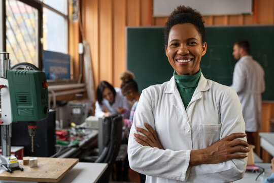 A confident female instructor leads a diverse group of students in a STEM class, equipped with modern educational tools.