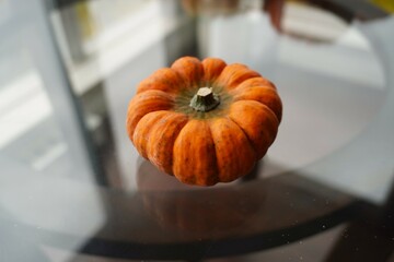 The orange small pumpkin on the glass table. Autumn mood