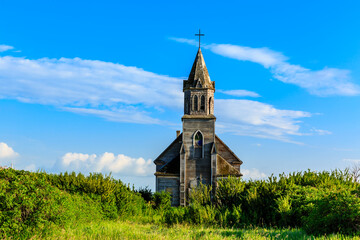 A small, old church sits in a field of grass