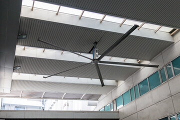 A large fan is suspended from the ceiling of a building