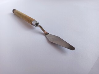 Art palette knives lie on a white art canvas. ainless painting palette knife with wooden handle. Palette knives, isolated on white. set new painting palette knives.