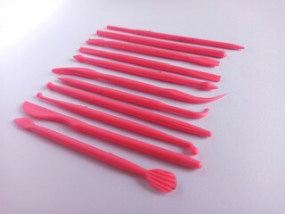 A row of pink fondant tools on a white background