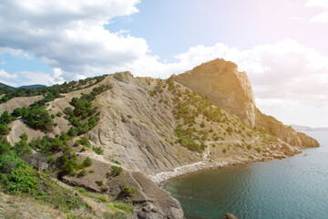 Coastal bay with rocky hills, sparse greenery, and boats in calm blue-green water. Ideal for themes of travel, exploration, and natural beauty