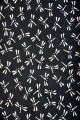 A Japanese Inden pattern featuring white dragonflies on a black background. The simple, repeating design symbolizes strength and renewal, showcasing elegance and traditional craftsmanship.