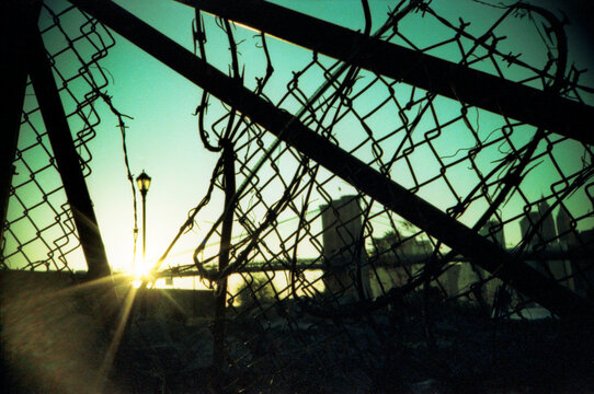 sunlight shinning through a broken fence with barbed wire, Brooklyn, New York City 