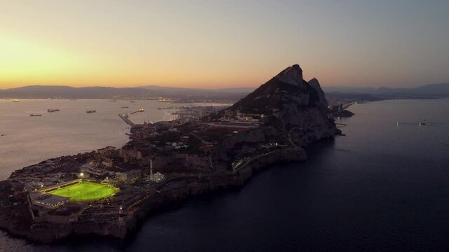 Spectacula aerial view of Gibraltar at sunset. Street lights on. Europa Sports Complex Stadium with night light on. Travel destination. Bay of Gibraltar. City of Gibraltar and La Linea, in background.