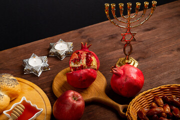 challah, honey, apple and pomegranate and burning candles on the table holiday meal Rosh Hashanah