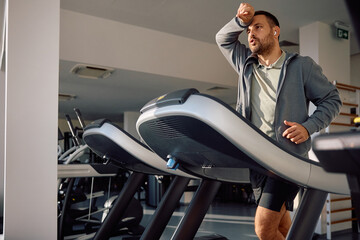 Sweaty athlete running on treadmill while exercising in gym.