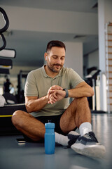 Male athlete using smart watch on break in health club.