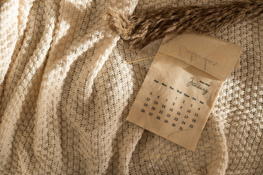 Minimal top view aesthetic composition with beige linen fabric calendar with January month 2025 and dry branch on a knitted blanket with copy space. Flat lay, New Year template - Powered by Adobe