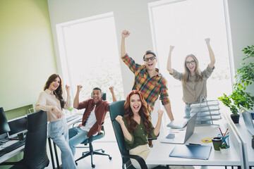 Photo of group five young corporate workers raise fists shout yeah workstation office business...