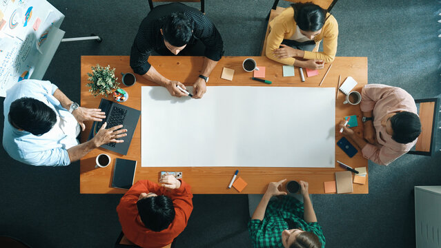 Top view of diverse group walking at boardroom and brainstorming idea. Smart startup team sharing marketing idea while project manager standing at whiteboard and present financial plan. Convocation.