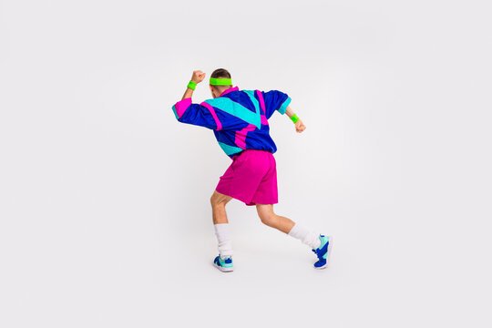 Energetic young man in retro sportswear showcasing vibrant style on white background