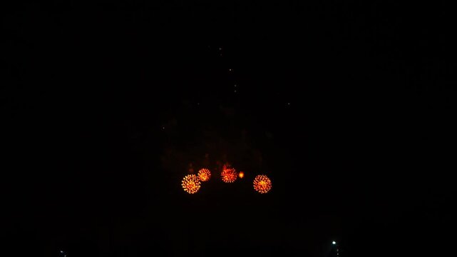 gold red blue sparks scattering fireworks on the black night sky over the city. General plan