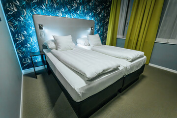 A sleek hotel room featuring two neatly arranged twin beds with white linens, accented by a vibrant...