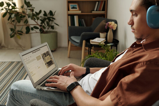 Creative male freelance designer typing on laptop keypad while creating digital content with AI image generator