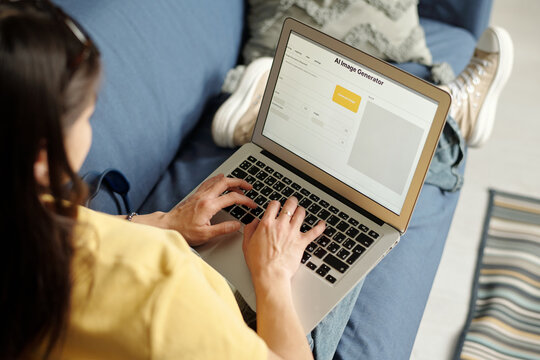 High angle of young woman in jeans and t-shirt touching keys of computer keypad during work with image generator