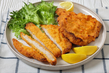 Pork Milanese with lettuce and lemon on a plate
