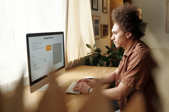 Side view of young male home office designer looking at computer screen with visual language model