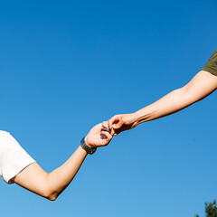 A man and woman lovingly hold each others hands beneath a serene blue sky, reveling in the warmth...