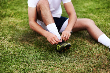Man, hands or tying laces with shoes on grass field for sport, running or workout preparation. Male person, legs or tie soccer boots for game, match or getting ready for football practice or training