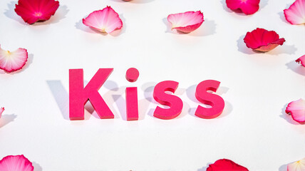 Kiss bold pink text surrounded by petals on white background