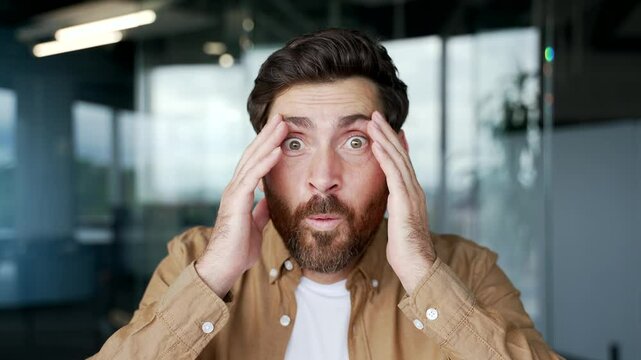 Webcam view. Amazed happy businessman looking surprised at camera or laptop screen sitting in office. Excited shocked man shot glasses. He saw pleasant content, read good news. celebrates success. Wow