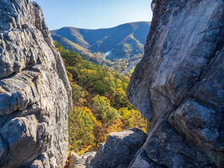 A gap between the cliffs at the summit of Seneca Rocks, opens up the fall colored mountain...