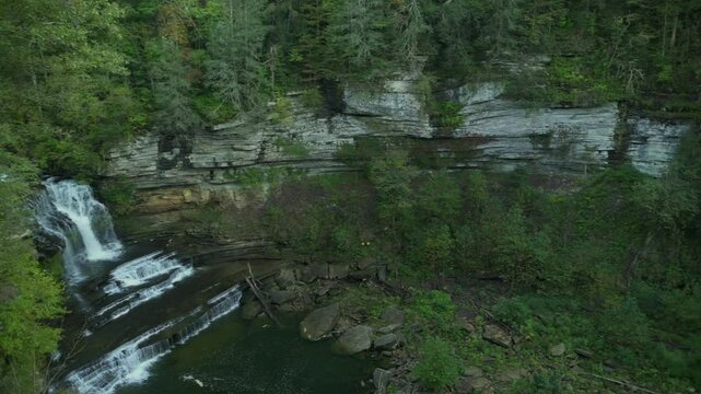 stunning view of cascading waterfall flowing into a clear pool, surrounded by lush green forest and rocky cliffs at Cummins Falls State Park, USA. cascading waterfall Cummins Falls State Park, USA