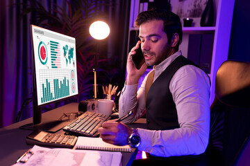 Smart businessman calling partner or investor on smartphone writing memo market data on paper work...