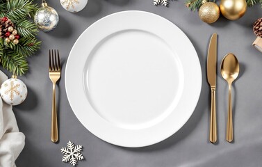 Grey table with an empty white plate and golden fork, knife, spoon and Christmas decorations 