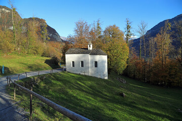 Old traditional swiss chapel in open air museum Ballenberg in the golden autumn. View of the Alps. Canton of Bern, Switzerland.
