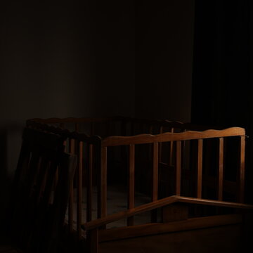 Cuna en fondo oscuro, iluminado de lado, estilo vintage.