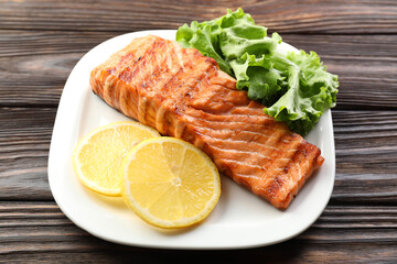 Delicious grilled salmon fillet served on wooden table, closeup