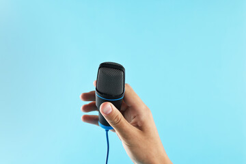 Man with microphone on light blue background, closeup