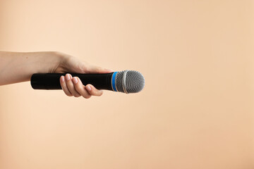 Woman with microphone on beige background, closeup. Space for text