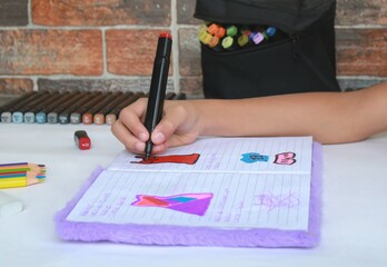 Mano de niña dibujando sobre un libro