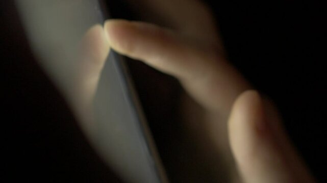 Girl Browsing Digital Tablet Computer With Finger at Night. Person Using Smartphone, Browsing on Social Network. Close-up Finger Scrolling Social Media App Feed or Reading News Feed Online. 